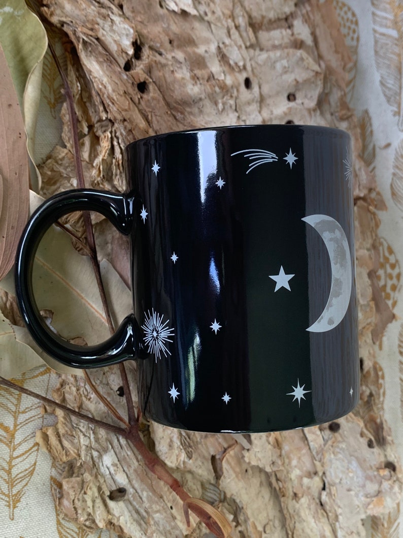 May include: Black ceramic mug with a white crescent moon, stars, and a shooting star design.