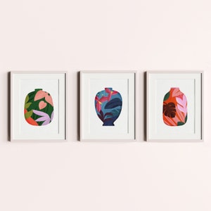 May include: Three framed prints of stylised floral patterned vases. The vases are in shades of blue, green, pink, and red. The frames are white.