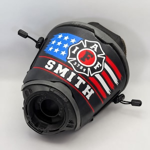 May include: A black tactical helmet cover featuring a graphic of a distressed American flag with a red horizontal stripe. The design includes a white firefighter emblem with the letters IAFF and the number 3794, and the name SMITH in white text.