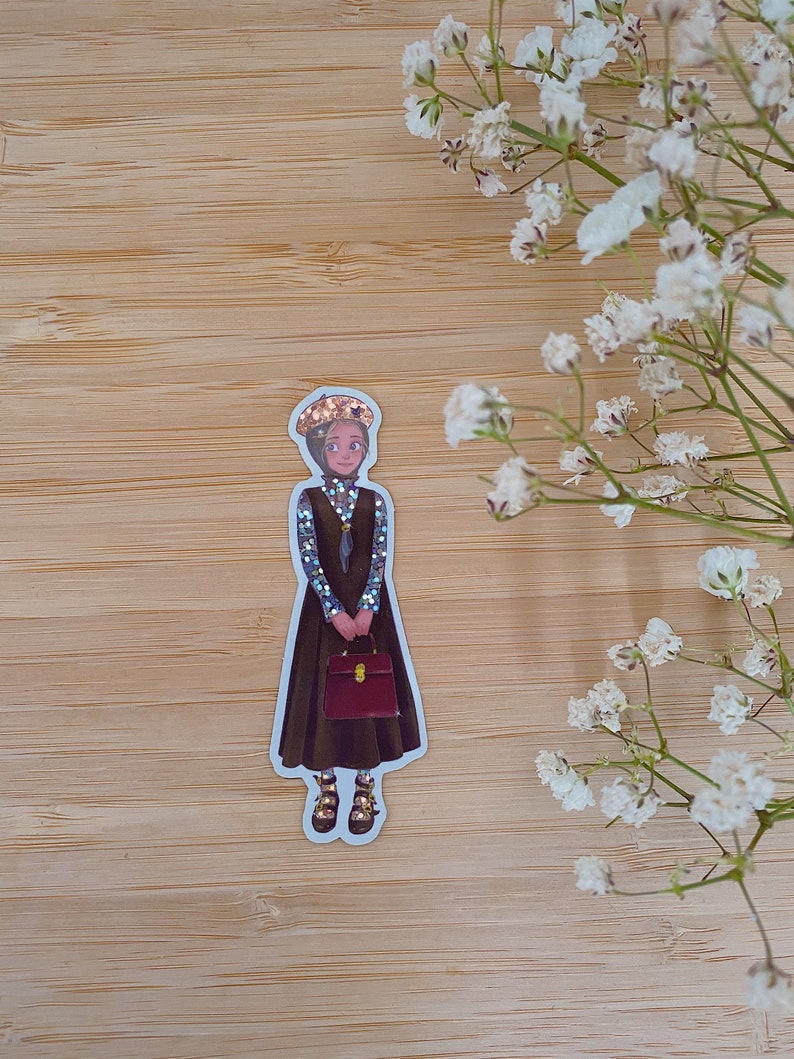 May include: A sticker of a cartoon woman wearing a brown dress, a blue and white patterned shirt, a gold crown, and brown shoes. She is holding a red briefcase.