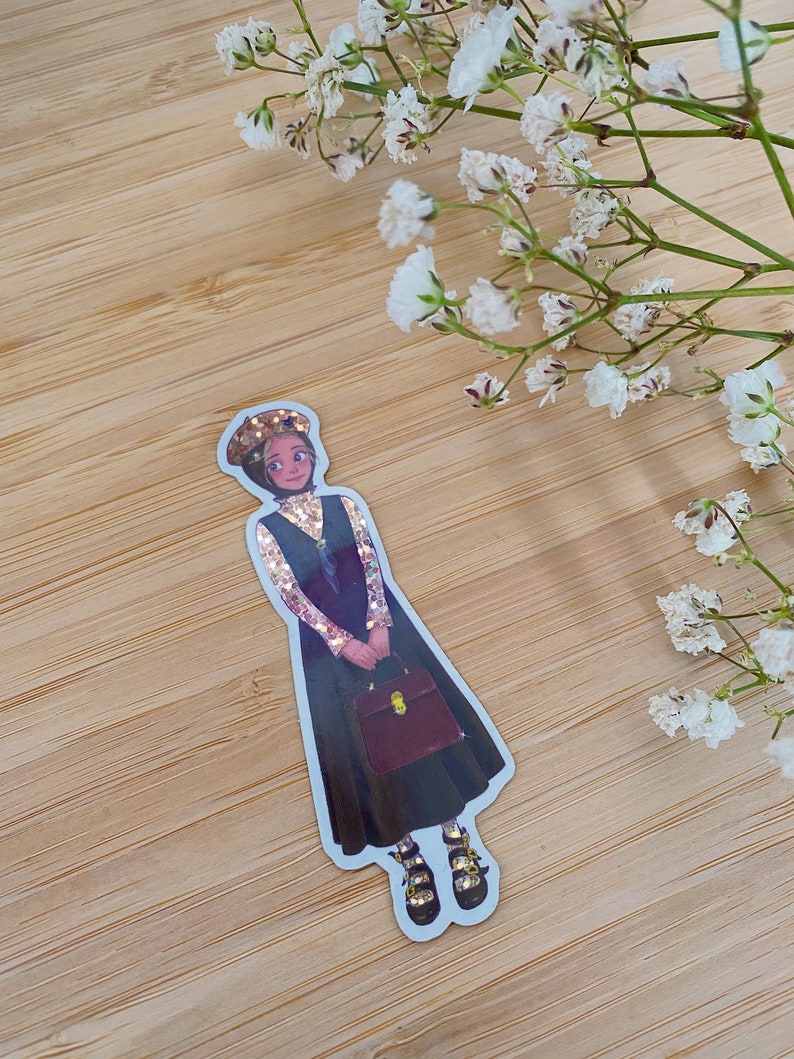 May include: A sticker of a cartoon woman wearing a black dress, a gold sparkly top, a black hat, and black shoes with gold accents. She is holding a brown briefcase. The sticker is on a wooden background.