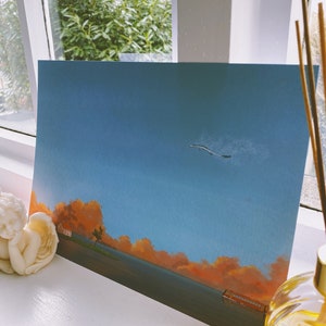 Pu&ograve; includere: Un dipinto di un paesaggio con un cielo blu, nuvole arancioni e una piccola casa in lontananza. Un uccello sta volando nel cielo.