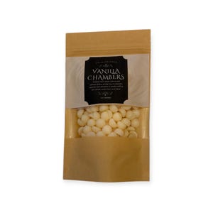 May include: A brown paper bag with a clear window, filled with white vanilla-flavored drops. The bag has a black label with the text "Vanilla Chambers" and details about the product. The bag contains 100 grams of product.