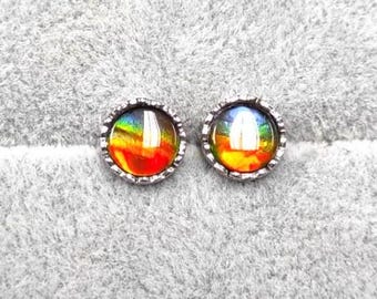 May include: A pair of silver stud earrings with iridescent round gemstones set in a textured silver bezel.