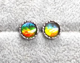 May include: A pair of iridescent earrings with a silver setting. The earrings feature a round, multi-colored stone with shades of green, yellow, orange, and red.