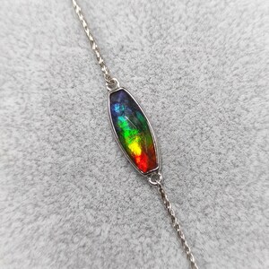 Peut inclure: Un collier en chaîne argent avec un pendentif ovale en pierre précieuse irisée arc-en-ciel.