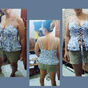 May include: A blue and white floral print top with a lace-up front and a ruffled hem. The top is worn with khaki shorts.