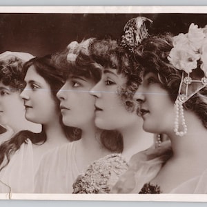May include: A sepia-toned vintage postcard featuring a layered photographic composition of five profiles of the same person. The individual wears various headpieces, including floral arrangements and pearl accents, with soft, draped clothing visible.