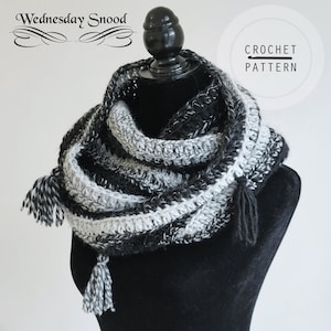 May include: A black and white crocheted snood with tassels. The snood is on a black mannequin. The text "Wednesday Snood" and "CROCHET PATTERN" is visible in the image.