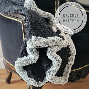 May include: A black and gray crochet blanket with a fluffy border. The blanket is draped over a black velvet chair with gold accents. The text "Jinxed Stitches Original Crochet Pattern Digital Download" is on a white circle.