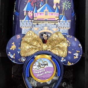 May include: A navy blue backpack and matching ear headband set. The backpack features a castle design with fireworks. The headband has a gold sequined bow and a 10 Years Happily Ever After emblem. The ears are decorated with Disney characters.
