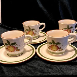 Puede incluir: Juego de cuatro tazas de té y platillos de cerámica blanca con un diseño floral verde y marrón con melocotones.