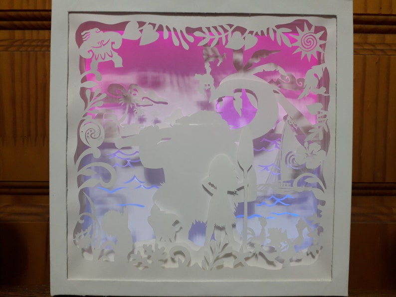 May include: A white, layered paper art piece depicting a tropical scene with a pink and purple gradient background. The artwork features silhouettes of characters, plants, and a boat, all within a white frame. The scene is illuminated with blue and pink lights.