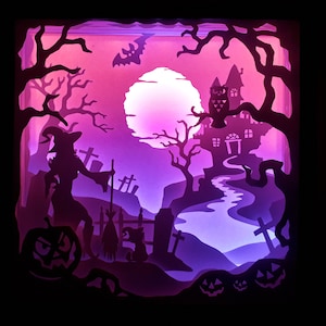 K&ouml;nnte beinhalten: Ein geschichtetes Papierkunstwerk, das eine Halloween-Szene darstellt. Eine Hexe, ein K&uuml;rbis und ein Spukhaus sind vor einem violett-rosa Farbverlaufshintergrund silhouettiert. Ein Vollmond und eine Fledermaus tragen zur gruseligen Atmosph&auml;re bei.