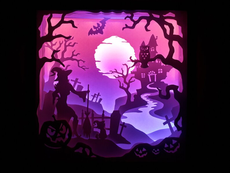 K&ouml;nnte beinhalten: Ein geschichtetes Papierkunstwerk, das eine Halloween-Szene darstellt. Eine Hexe, ein K&uuml;rbis und ein Spukhaus sind vor einem violett-rosa Farbverlaufshintergrund silhouettiert. Ein Vollmond und eine Fledermaus tragen zur gruseligen Atmosph&auml;re bei.