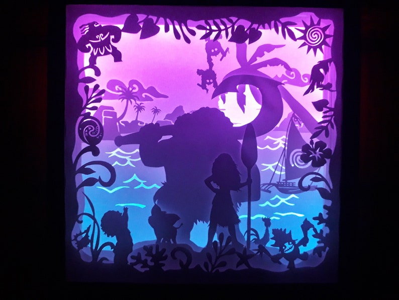 May include: A layered paper art piece featuring silhouettes of characters and tropical scenery. The artwork depicts a beach scene with a sailboat, palm trees, and figures, illuminated with purple and blue lighting. The piece is framed with decorative cutouts.