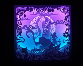 May include: A layered paper art piece depicting a scene with characters and elements from a popular animated movie. The artwork features silhouettes in shades of blue, purple, and white, with a bright light illuminating the scene from behind. The design includes a boat, characters, and tropical foliage.