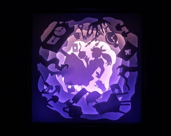 May include: A layered paper art piece depicting scenes from Alice in Wonderland. Silhouettes of characters, clocks, and playing card suits are illuminated with purple and white light, creating a whimsical and enchanting effect.
