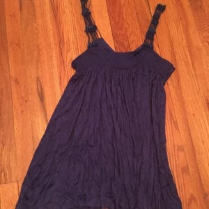 Puede incluir: Un vestido azul oscuro con una falda fluida y tirantes tejidos. Los tirantes son de un tono azul m&aacute;s oscuro y presentan peque&ntilde;os elementos decorativos. El vestido est&aacute; hecho de una tela suave y ligera.