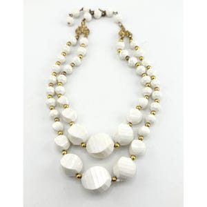 May include: A white double strand necklace with gold accents. The necklace is made of large, round, faceted beads.