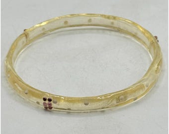 May include: A clear, gold-toned bangle bracelet with small, evenly spaced holes. The bracelet features clusters of small, round, pink gemstones. The overall design is simple and elegant, suitable for everyday wear or special occasions.