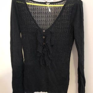 Pu&ograve; includere: Top nero a maniche lunghe con scollo a V e chiusura con bottoni. Il top presenta un delicato motivo a pizzo sulla parte superiore del petto e un dettaglio a balze sul davanti. Il top &egrave; realizzato in un materiale morbido e strutturato.