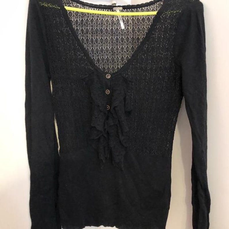 Pu&ograve; includere: Top nero a maniche lunghe con scollo a V e chiusura con bottoni. Il top presenta un delicato motivo a pizzo sulla parte superiore del petto e un dettaglio a balze sul davanti. Il top &egrave; realizzato in un materiale morbido e strutturato.
