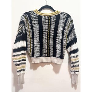 Puede incluir: Un su&eacute;ter de rayas corto en negro, blanco y amarillo.