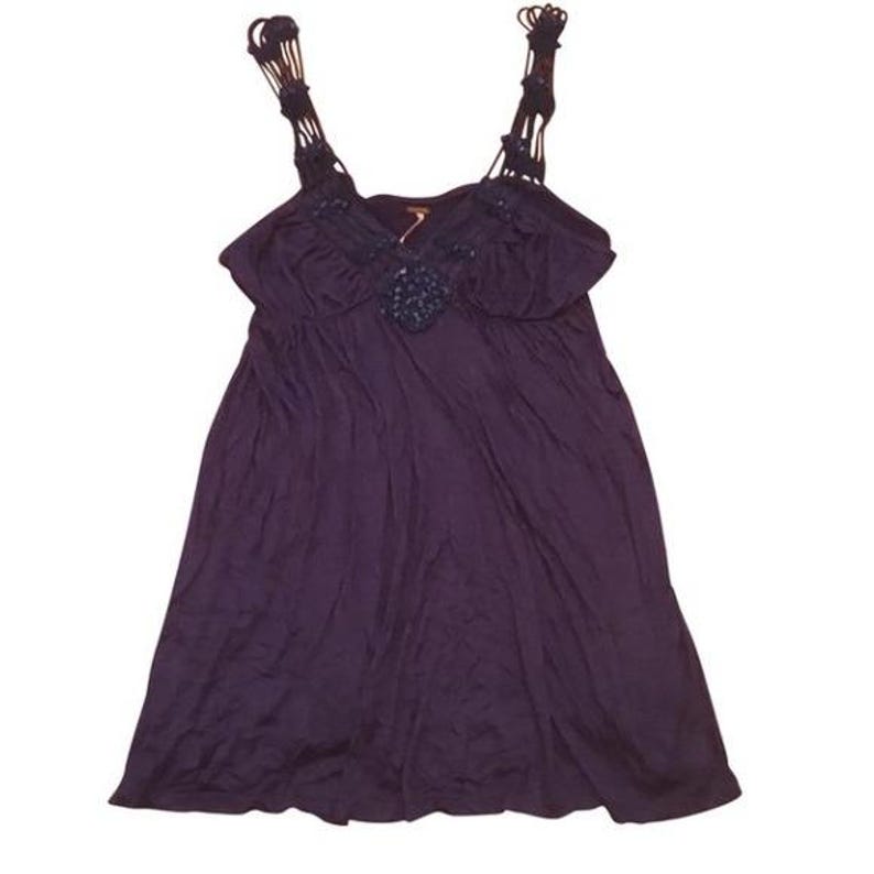 Puede incluir: Vestido morado oscuro con tirantes de macram&eacute; y corpi&ntilde;o fruncido. El vestido presenta un adorno decorativo en el centro del busto. La tela parece suave y fluida, creando una silueta relajada. Adecuado para ropa informal.