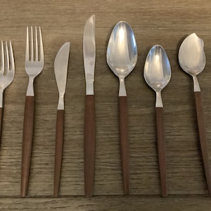 May include: A set of stainless steel silverware with wooden handles. The set includes forks, knives, and spoons. The silverware is arranged on a wooden surface, showcasing a classic and elegant design.