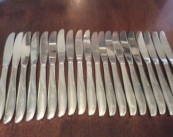 May include: A set of 18 silver dinner knives with a decorative swirl design on the handle.