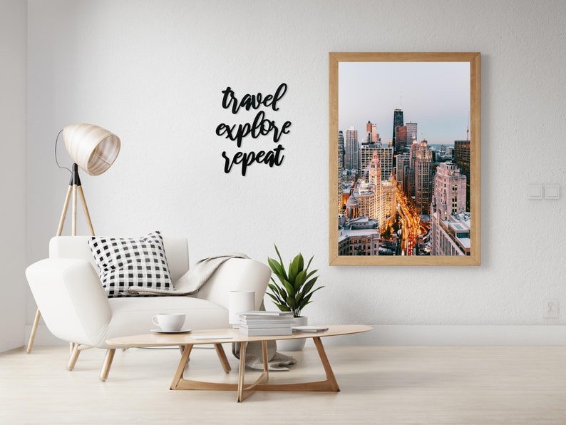 May include: A framed photograph of a city skyline at dusk. The photo shows a cityscape with tall buildings and street lights. The quote "travel explore repeat" is written on the wall above the photo.