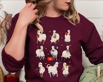 May include: A burgundy sweatshirt featuring a Halloween-themed design of cartoon horses dressed as ghosts. The horses are depicted in various poses, some holding trick-or-treat bags. The sweatshirt is part of a fall or Halloween collection.
