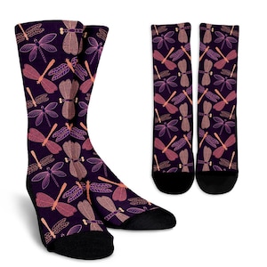 May include: A pair of purple socks with a pattern of pink and orange dragonflies. The socks are shown in a close-up view, with the left sock folded down to show the pattern.