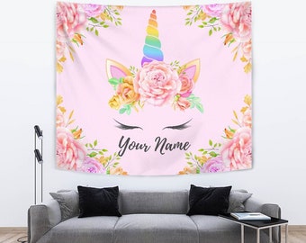 May include: Pink tapestry with a unicorn face made of flowers. The unicorn has a rainbow horn and closed eyes. The text "Your Name" is printed below the unicorn.