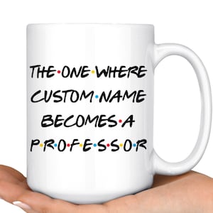 Könnte beinhalten: Weiße Keramik-Kaffeetasse mit einer schwarz-weißen Grafik, die "The One Where CUSTOM NAME Becomes A Professor" mit bunten Punkten zwischen den Wörtern lautet.