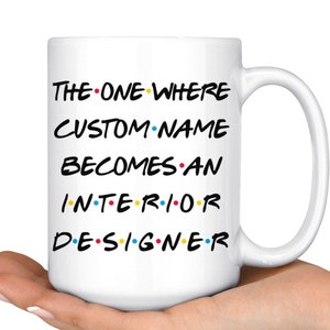 May include: White ceramic mug with a black and white graphic that reads "THE ONE WHERE CUSTOM NAME BECOMES AN INTERIOR DESIGNER".