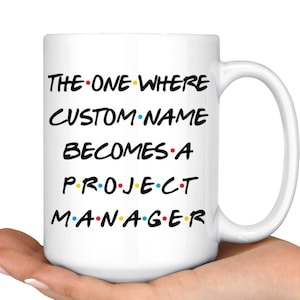 May include: White ceramic mug with a black and white graphic that says "THE ONE WHERE CUSTOM NAME BECOMES A PROJECT MANAGER" with colorful dots between the words.