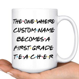 May include: White ceramic coffee mug with a black and white graphic that says "The One Where CUSTOM NAME Becomes A First Grade Teacher" with colorful dots between the words.
