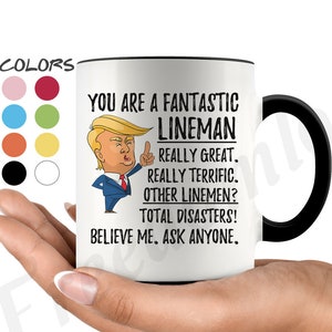 Könnte beinhalten: Eine weiße Keramik-Kaffeetasse mit schwarzem Henkel. Die Tasse zeigt ein Cartoon-Bild von Donald Trump mit dem Text "You are a fantastic lineman. Really great. Really terrific. Other linemen? Total disasters! Believe me. Ask anyone."