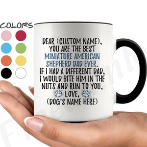 Puede incluir: Taza de café de cerámica blanca con borde y asa negros. La taza presenta un diseño azul y blanco con el texto "DEAR (CUSTOM NAME), YOU ARE THE BEST MINIATURE AMERICAN SHEPHERD DAD EVER. IF I HAD A DIFFERENT DAD, I WOULD BITE HIM IN THE NUTS AND RUN TO YOU. LOVE, (DOG'S NAME HERE)"