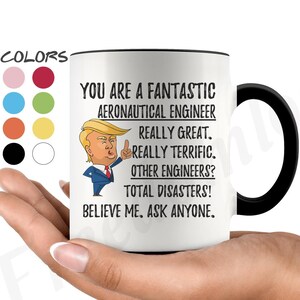 Puede incluir: Taza de café de cerámica blanca con borde y asa negros. La taza presenta una imagen de dibujos animados de un hombre con corbata roja sobre un fondo blanco. El texto en la taza dice: "You are a fantastic aeronautical engineer. Really great. Really terrific. Other engineers? Total disasters! Believe me. Ask anyone."