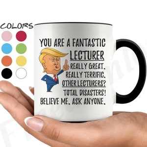 Könnte beinhalten: Eine weiße Keramik-Kaffeetasse mit schwarzem Rand und Henkel. Die Tasse zeigt ein Cartoon-Bild eines Mannes mit blonden Haaren und einer roten Krawatte. Der Text auf der Tasse lautet "You are a fantastic lecturer. Really great. Really terrific. Other lecturers? Total disasters! Believe me. Ask anyone."