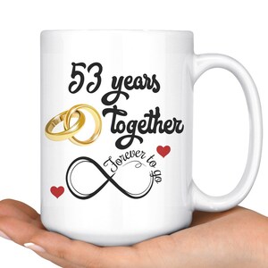 May include: White ceramic coffee mug with black text that reads "53 years together Forever to go" with two gold rings and two red hearts.