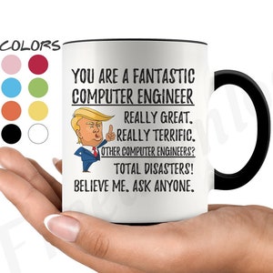 Op de afbeelding: Een witte keramische koffiemok met een zwart handvat. De mok heeft een zwarte rand en bevat een cartoonafbeelding van een man met blond haar en een rode stropdas. De tekst op de mok luidt "You are a fantastic computer engineer. Really great. Really terrific. Other computer engineers? Total disasters! Believe me. Ask anyone."