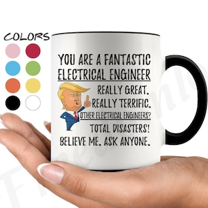 May include: White ceramic coffee mug with a black handle. The mug has a black rim and features a cartoon image of a man with a thumbs up. The text on the mug reads "You are a fantastic electrical engineer. Really great. Really terrific. Other electrical engineers? Total disasters! Believe me. Ask anyone."