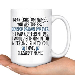 Puede incluir: Taza de café de cerámica blanca con un diseño en negro y azul. La taza dice "Querido (Nombre personalizado), Eres el mejor papá dragón barbudo de todos los tiempos. Si tuviera un papá diferente, le mordería las nueces y correría hacia ti. Con amor, (Nombre del lagarto)"