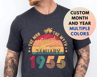 Może przedstawiać: Szary t-shirt z nadrukiem w stylu vintage. Grafika przedstawia zachód słońca z palmami i tekstem "The Man The Myth Legend January 1955".