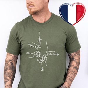 May include: Military green t-shirt with a white line drawing of hands holding each other. Names are written above the hands: Papa, Hugo, Alex, Sacha, and Lucie. The color of the shirt is described as military green.