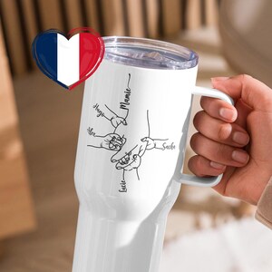 May include: White insulated travel mug with a handle, featuring a clear lid and a design of connected hands with names. The names "Alex", "Lucie", "Sacha", "Hugo", and "Mamie" are written in black script. A French flag heart is on the left.